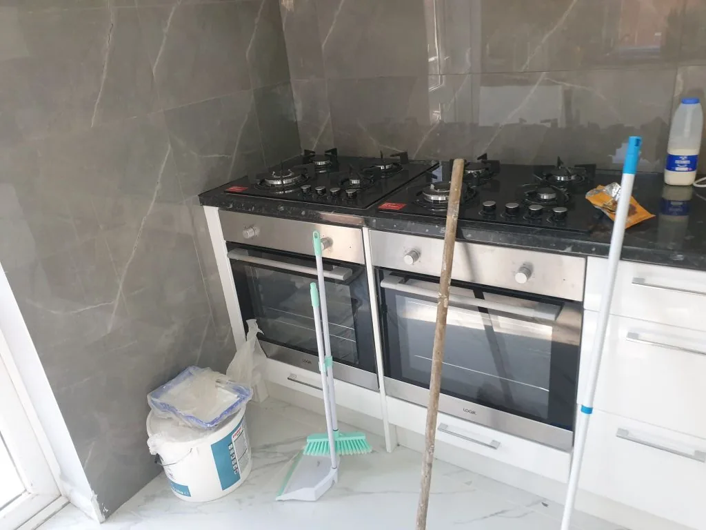 Kitchen with a built-in gas hob and ovens and a dark stone-effect worktop